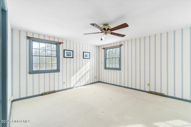 carpeted spare room featuring ceiling fan and a healthy amount of sunlight