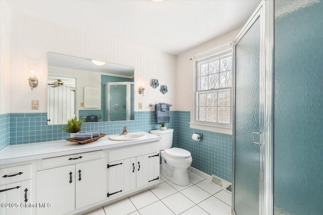 bathroom with walk in shower, tile patterned floors, toilet, tile walls, and vanity