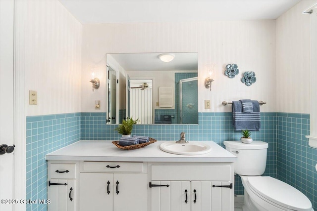 bathroom with a shower with door, vanity, tile walls, and toilet