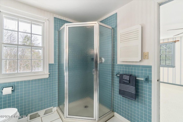 bathroom with tile walls, an enclosed shower, tile patterned floors, and toilet