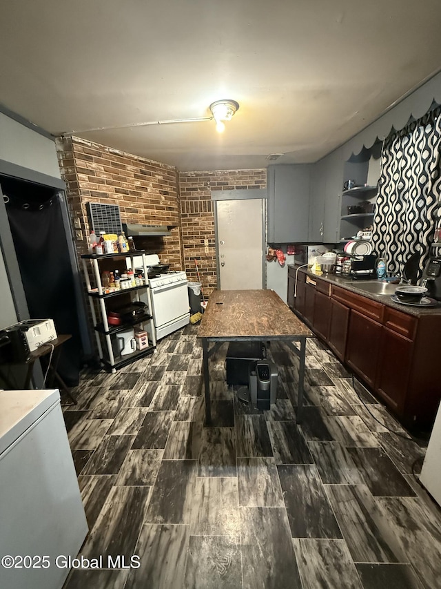 kitchen with sink, white gas stove, and brick wall