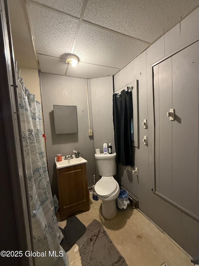 bathroom with toilet, sink, a drop ceiling, and concrete floors