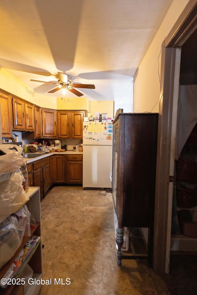 kitchen featuring fridge, ceiling fan, and sink