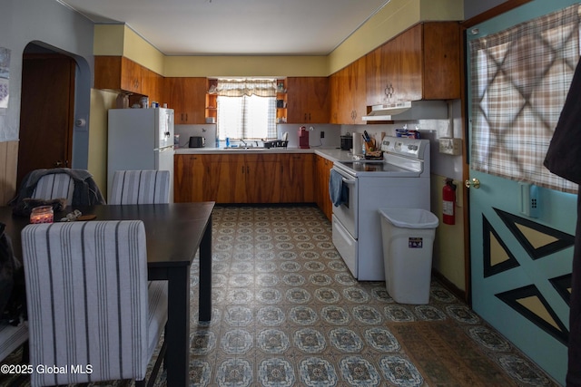 kitchen with white appliances, radiator heating unit, and sink