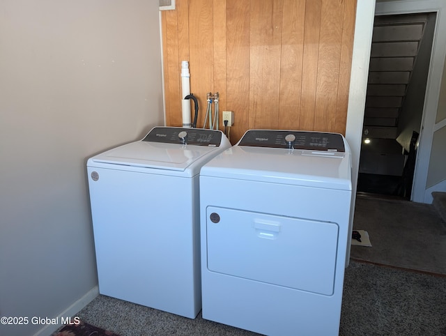 laundry area with laundry area, carpet flooring, wood walls, and washing machine and clothes dryer