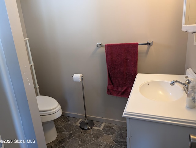 bathroom with toilet, baseboards, and vanity