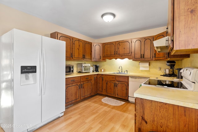 kitchen with sink, white appliances, and light wood-type flooring