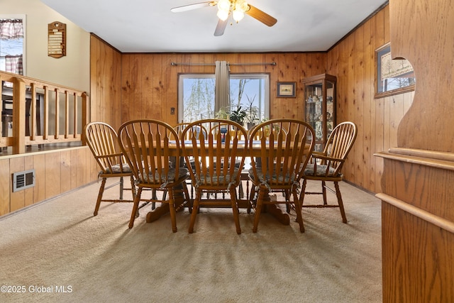 carpeted dining space with wooden walls and ceiling fan