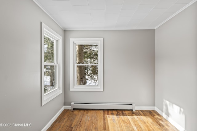 empty room featuring hardwood / wood-style flooring, a baseboard radiator, and crown molding