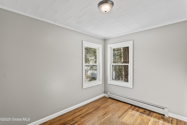 spare room featuring a baseboard radiator, ornamental molding, and light hardwood / wood-style floors