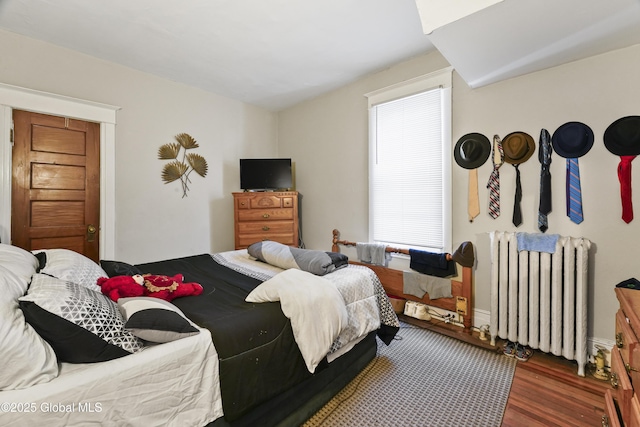 bedroom featuring radiator heating unit and dark hardwood / wood-style flooring