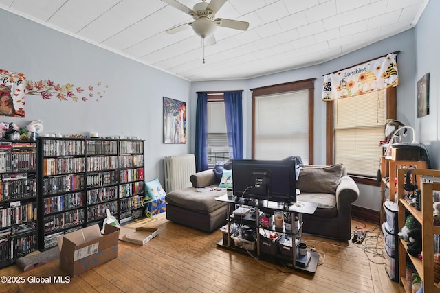 living area featuring hardwood / wood-style flooring, radiator heating unit, and ceiling fan