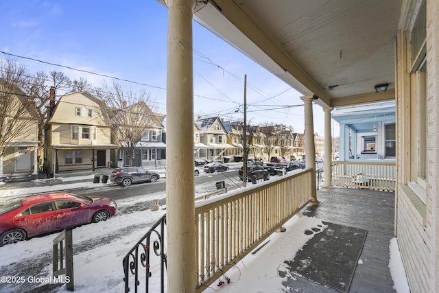 snow covered back of property featuring covered porch