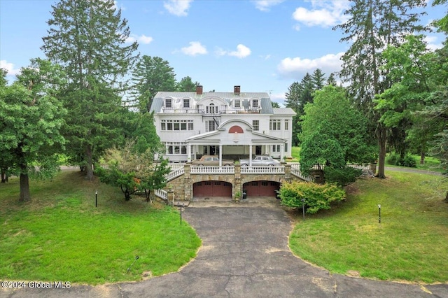 view of front of home with a garage, a front lawn, and a balcony