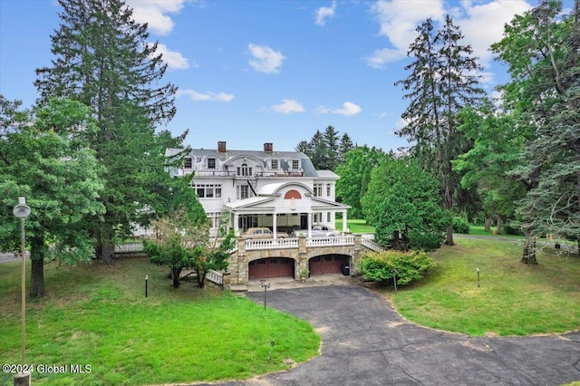 view of front of house with a garage, a balcony, and a front lawn