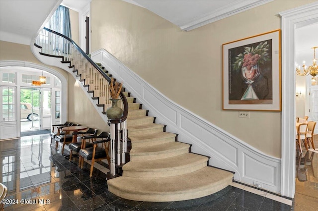 staircase with crown molding, a towering ceiling, and a chandelier