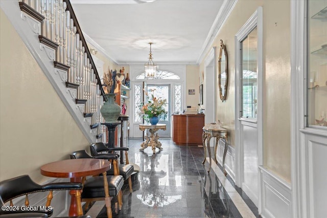 foyer with an inviting chandelier and crown molding