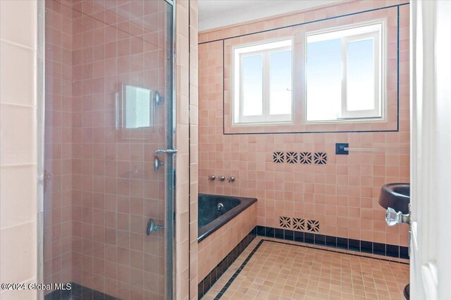 bathroom with tile patterned floors, shower with separate bathtub, and tile walls