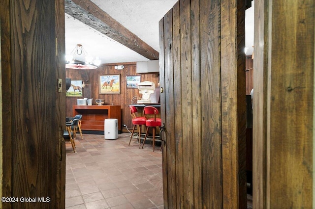 bar with beamed ceiling, a textured ceiling, and wood walls