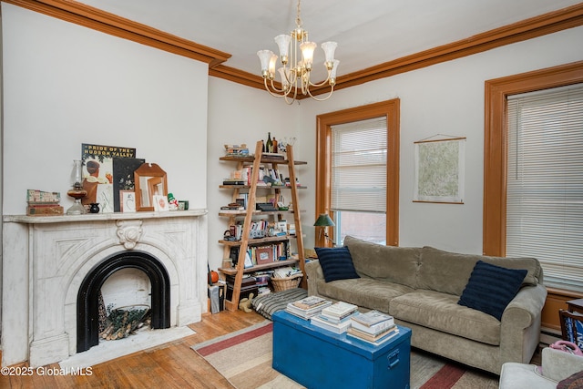 living room with hardwood / wood-style floors, a notable chandelier, a high end fireplace, and ornamental molding