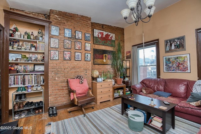 sitting room with hardwood / wood-style flooring, brick wall, and a chandelier