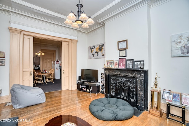 living room featuring a notable chandelier, hardwood / wood-style floors, ornamental molding, and a premium fireplace