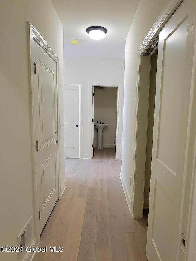 corridor featuring sink and light hardwood / wood-style flooring