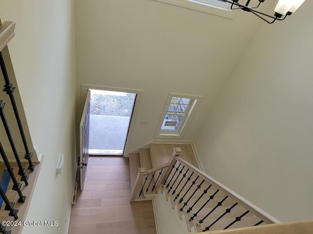 stairway featuring an inviting chandelier, hardwood / wood-style flooring, and a high ceiling