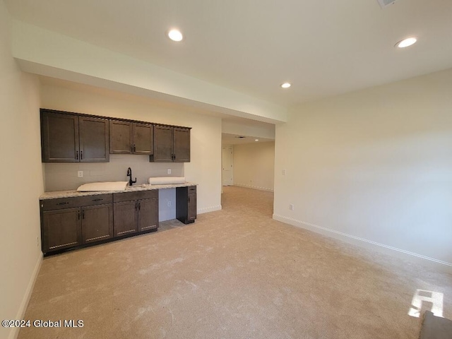 kitchen featuring light colored carpet and dark brown cabinets