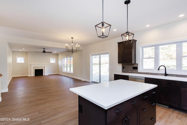 kitchen featuring light hardwood / wood-style flooring, dark brown cabinets, a kitchen island, decorative backsplash, and decorative light fixtures