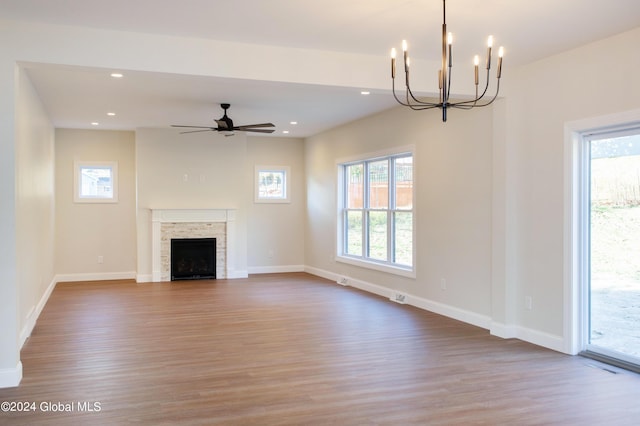 unfurnished living room featuring ceiling fan with notable chandelier, a wealth of natural light, and light hardwood / wood-style flooring