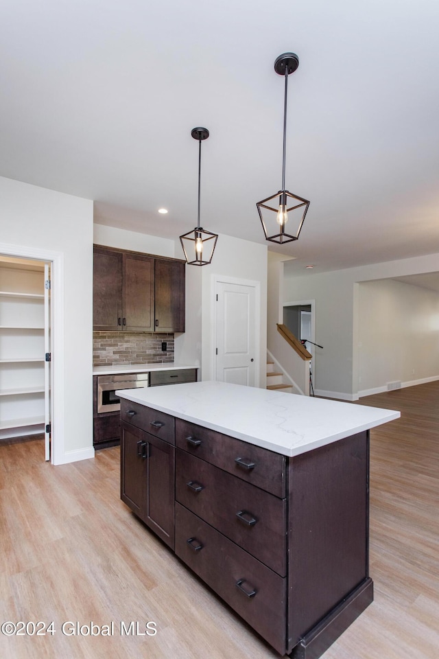 kitchen with dark brown cabinetry, hanging light fixtures, light hardwood / wood-style flooring, and a center island