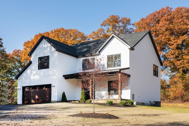 modern inspired farmhouse featuring a garage, a front lawn, and central air condition unit