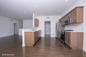 kitchen featuring sink, stainless steel appliances, dark hardwood / wood-style floors, decorative backsplash, and kitchen peninsula