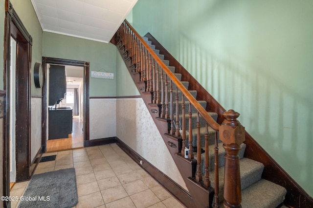 stairs featuring tile patterned floors, wainscoting, and crown molding