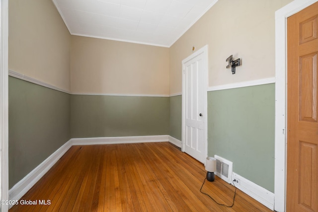 unfurnished room with baseboards, visible vents, ornamental molding, and hardwood / wood-style flooring