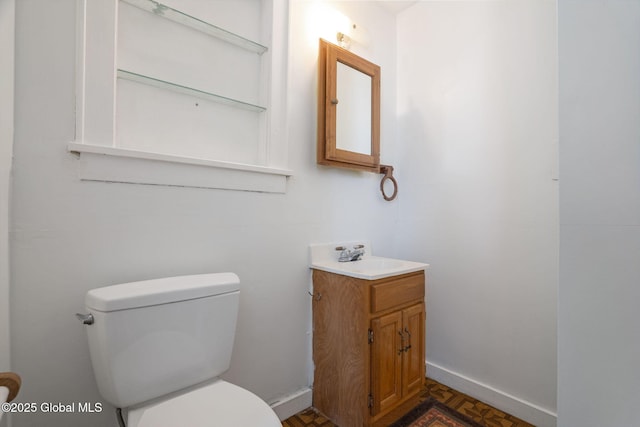 bathroom with baseboards, toilet, and vanity