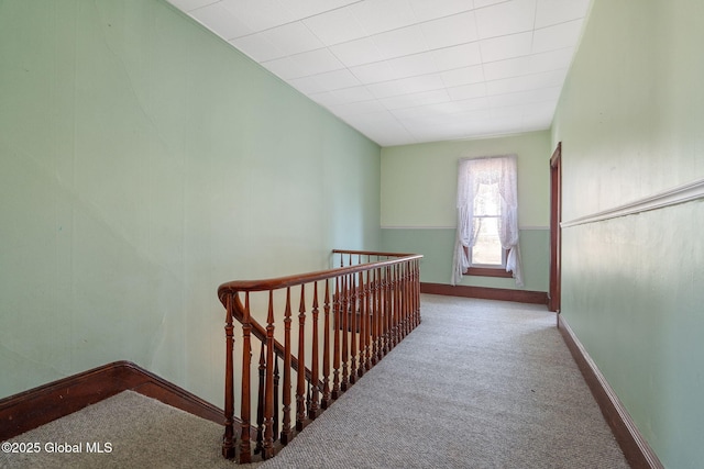 hall featuring an upstairs landing, carpet, and baseboards