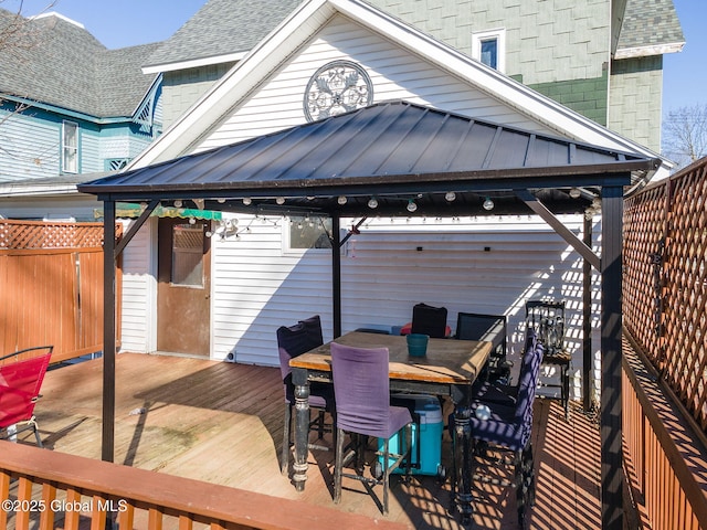 wooden terrace with outdoor dining space, a gazebo, and fence