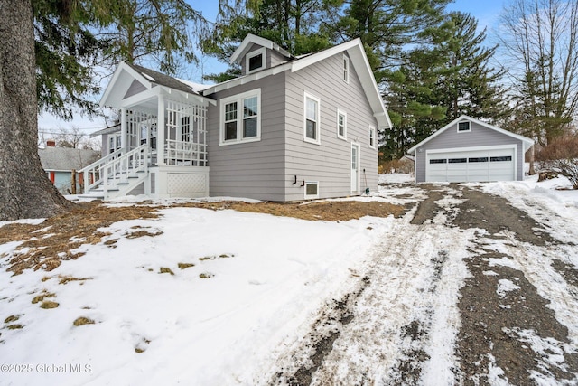 snow covered property with a garage and an outdoor structure