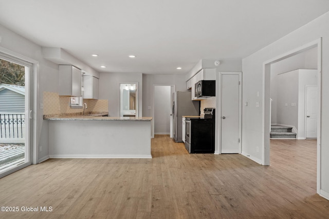 kitchen with tasteful backsplash, white cabinetry, stainless steel range with electric stovetop, kitchen peninsula, and light hardwood / wood-style flooring