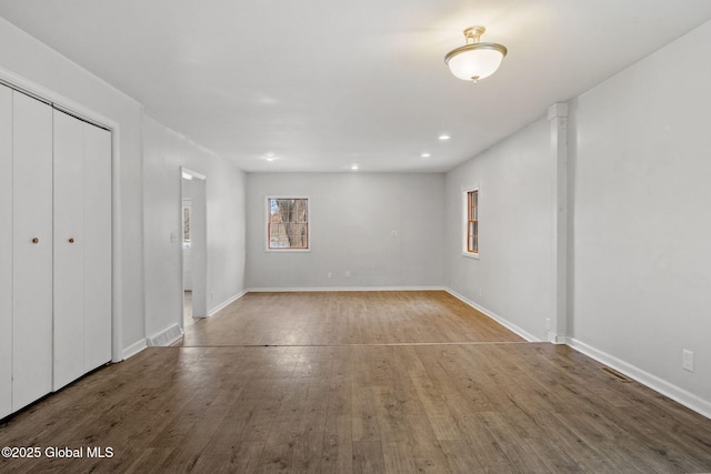 interior space featuring hardwood / wood-style flooring, decorative columns, multiple windows, and a closet