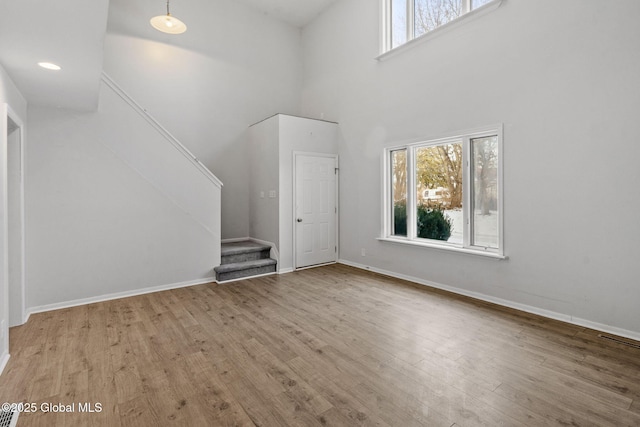 unfurnished living room with a towering ceiling and light hardwood / wood-style flooring