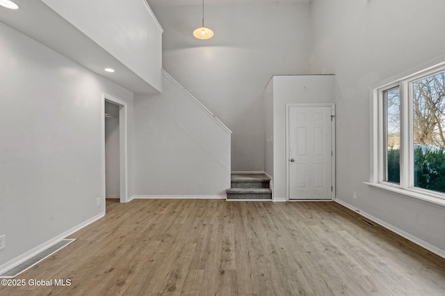 bonus room featuring a towering ceiling, a wealth of natural light, and light wood-type flooring