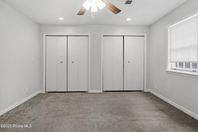 unfurnished bedroom with multiple closets, ceiling fan, and light carpet