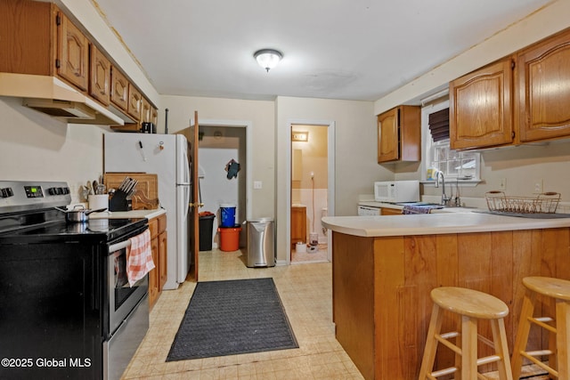 kitchen with sink, stainless steel electric stove, kitchen peninsula, and a kitchen bar