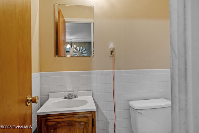 bathroom with vanity, toilet, and tile walls