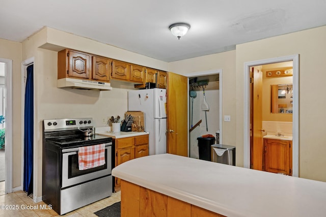 kitchen with white refrigerator, sink, and stainless steel range with electric cooktop