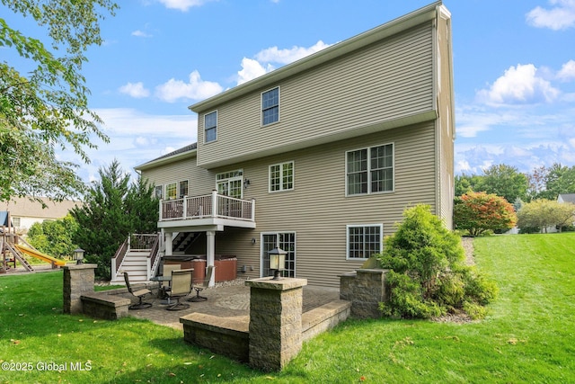 back of property with a lawn, a deck, and a patio area