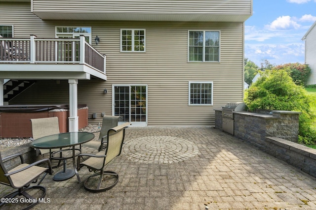 rear view of house featuring a hot tub, a balcony, area for grilling, and a patio area